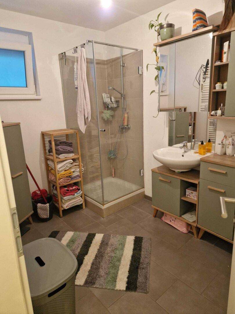 Modernes Badezimmer mit Duschkabine, Waschbecken und Holzmöbeln.