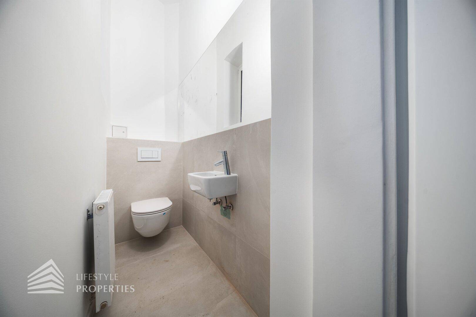 Modernes Gäste-WC mit Wand-WC, kleinem Waschbecken und Heizkörper.