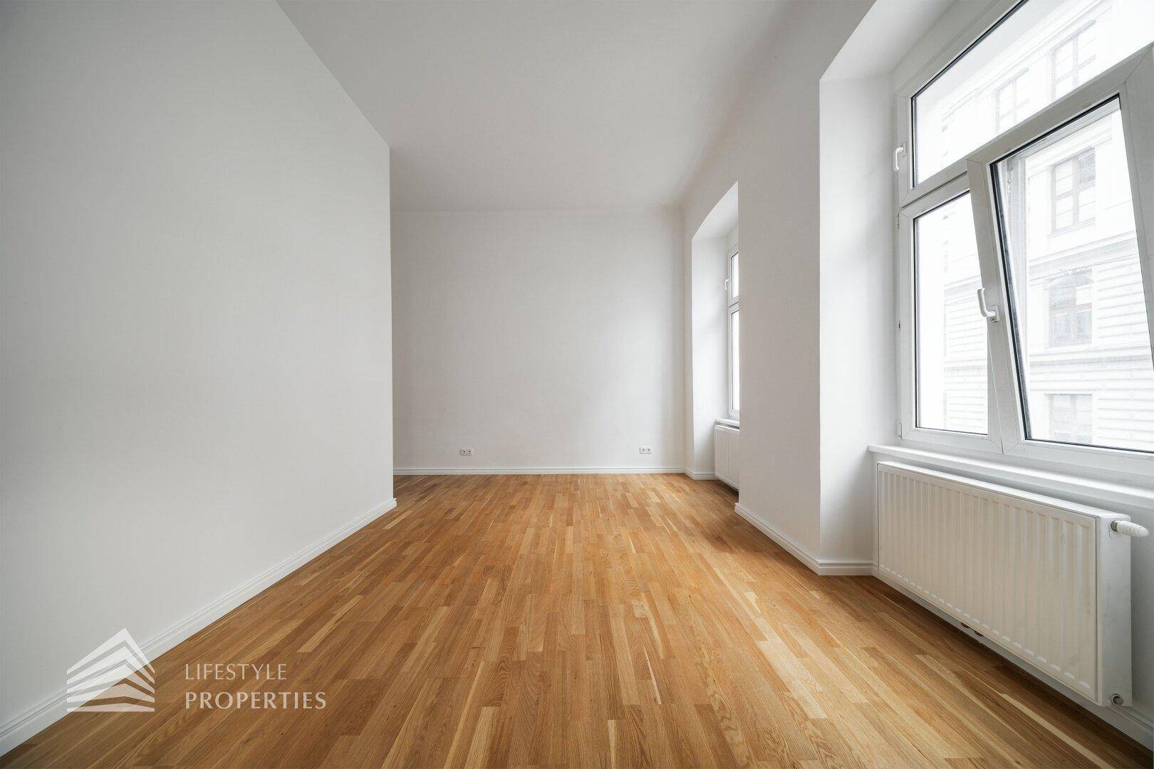 Geräumiges, helles Zimmer mit Parkettboden und großen Fenstern, bietet vielseitige Nutzungsmöglichkeiten.
