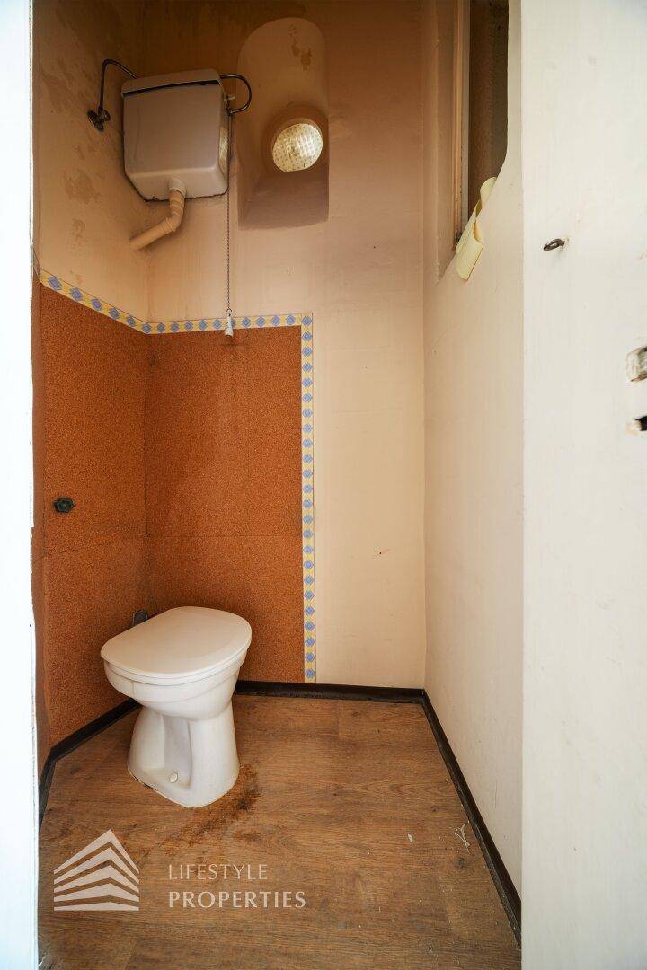 Kleines WC mit Toilette und Fenster, ausgestattet mit einer ungewöhnlichen Wandverkleidung.