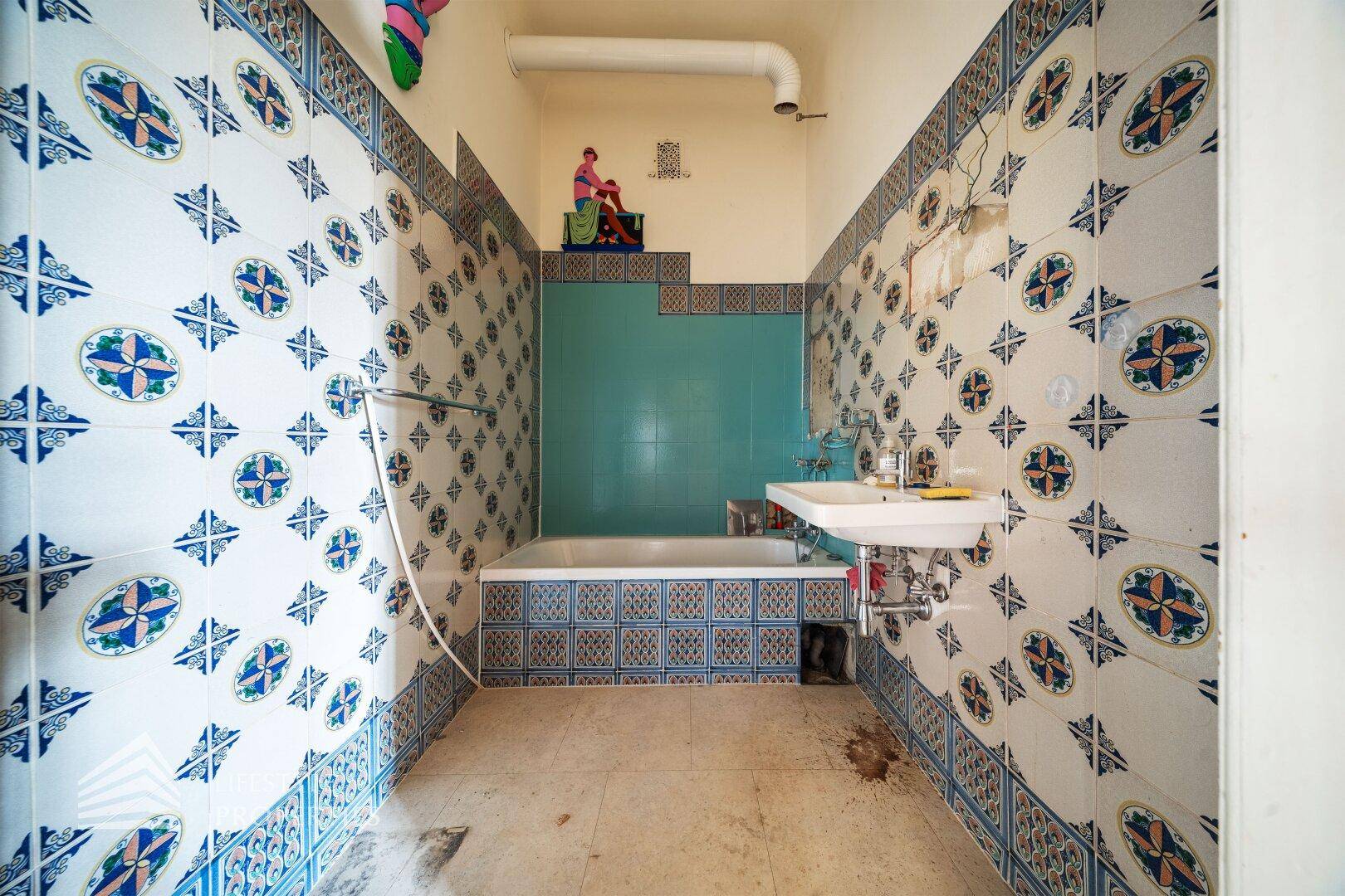 Badezimmer mit auffälligen blau-weißen Fliesen, Badewanne und Waschbecken im Vintage-Stil.