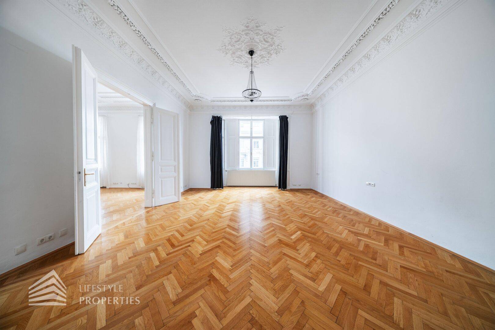 Großes, leeres Wohnzimmer mit Fischgrätparkett und hohen Decken, bereit für individuelle Gestaltung.