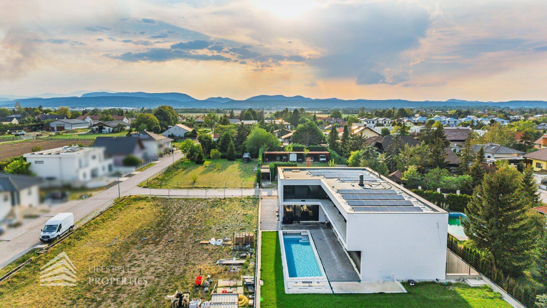 Luxuriöse Villa mit Pool und weitem Blick auf die Landschaft und die fernen Berge unter bewölktem Himmel.