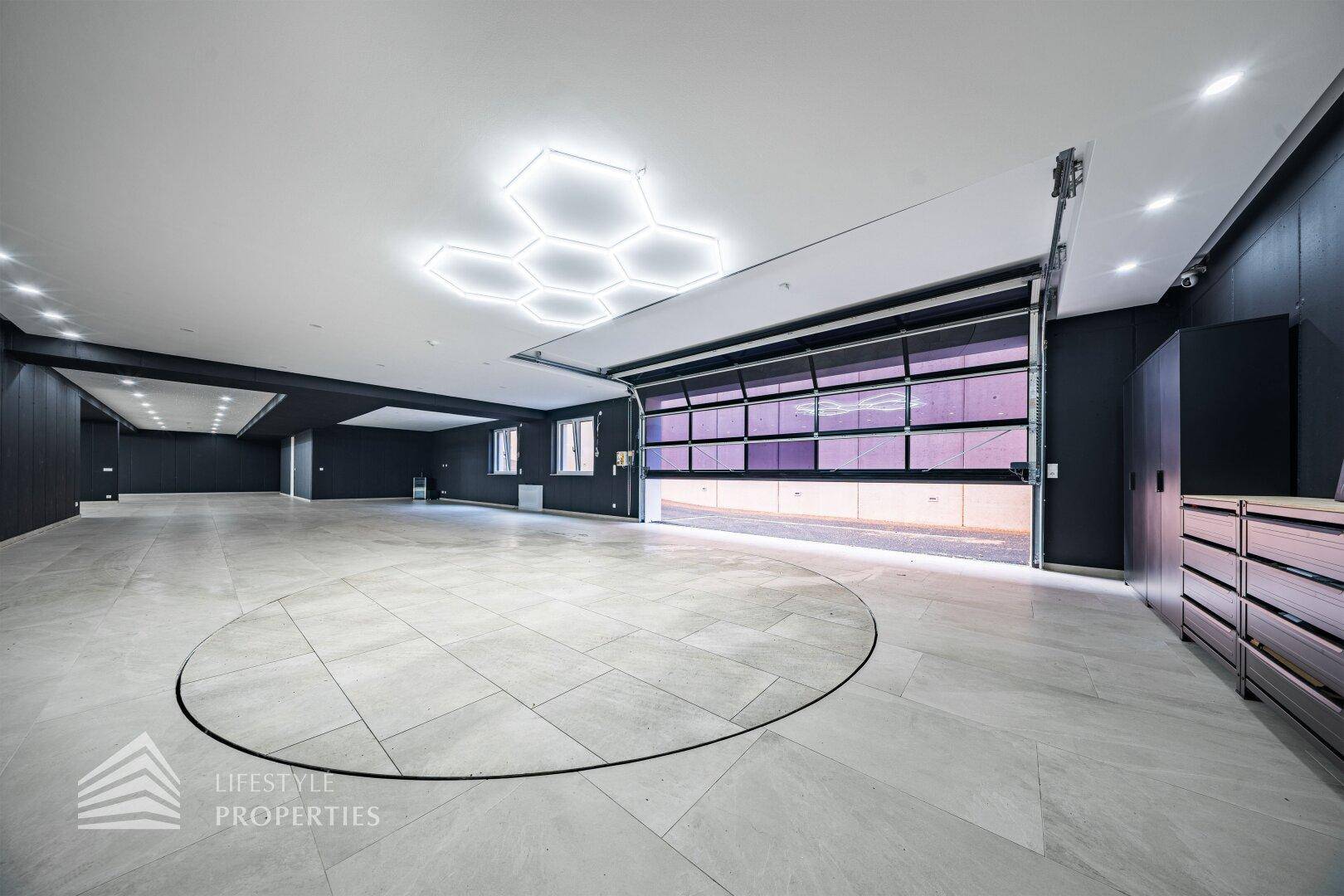 Geräumige Garage mit modernem Design, Fliesenboden und auffälliger Deckenbeleuchtung.