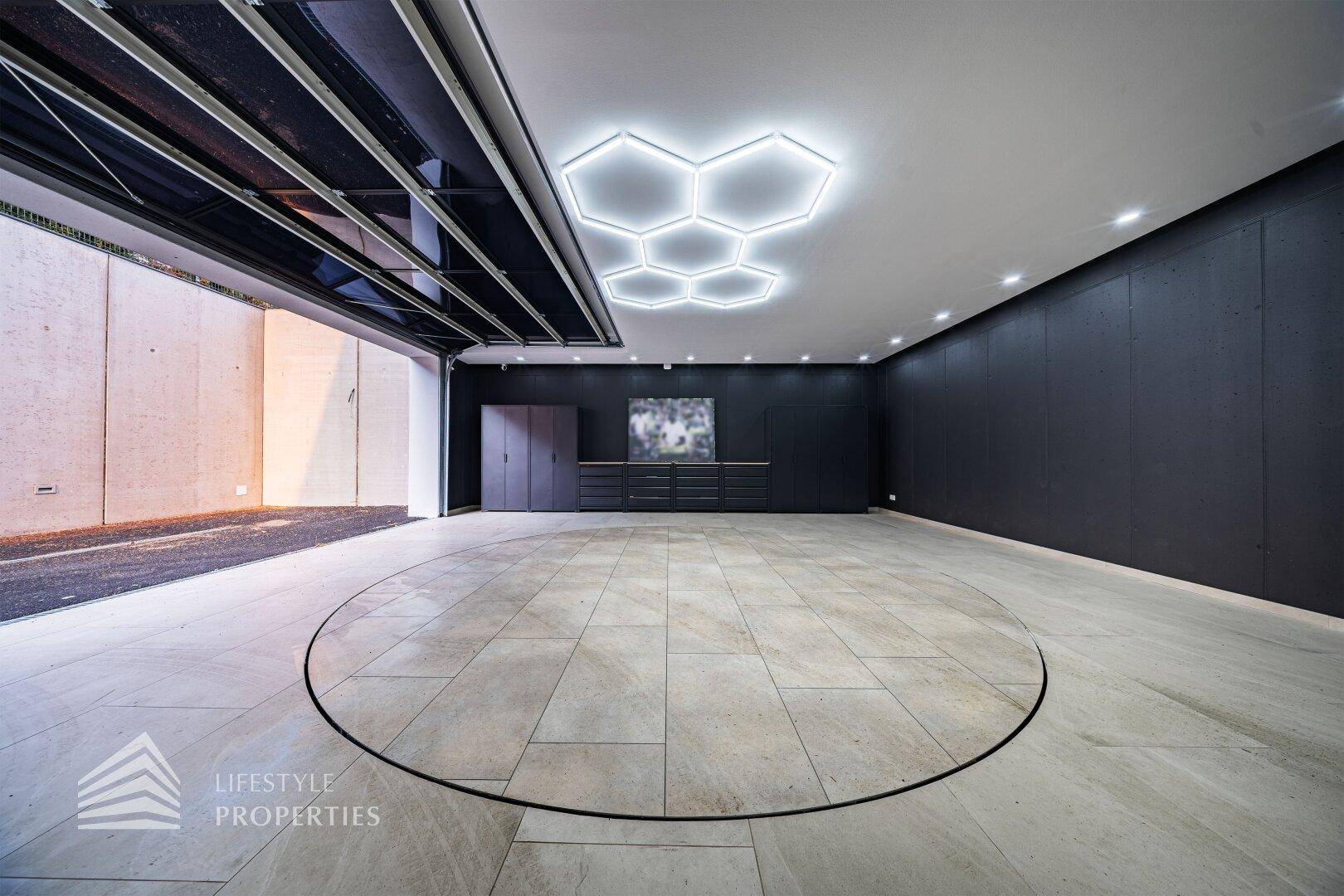 Geräumige Garage mit Fliesenboden, kreisförmigem Designelement und moderner Deckenbeleuchtung.