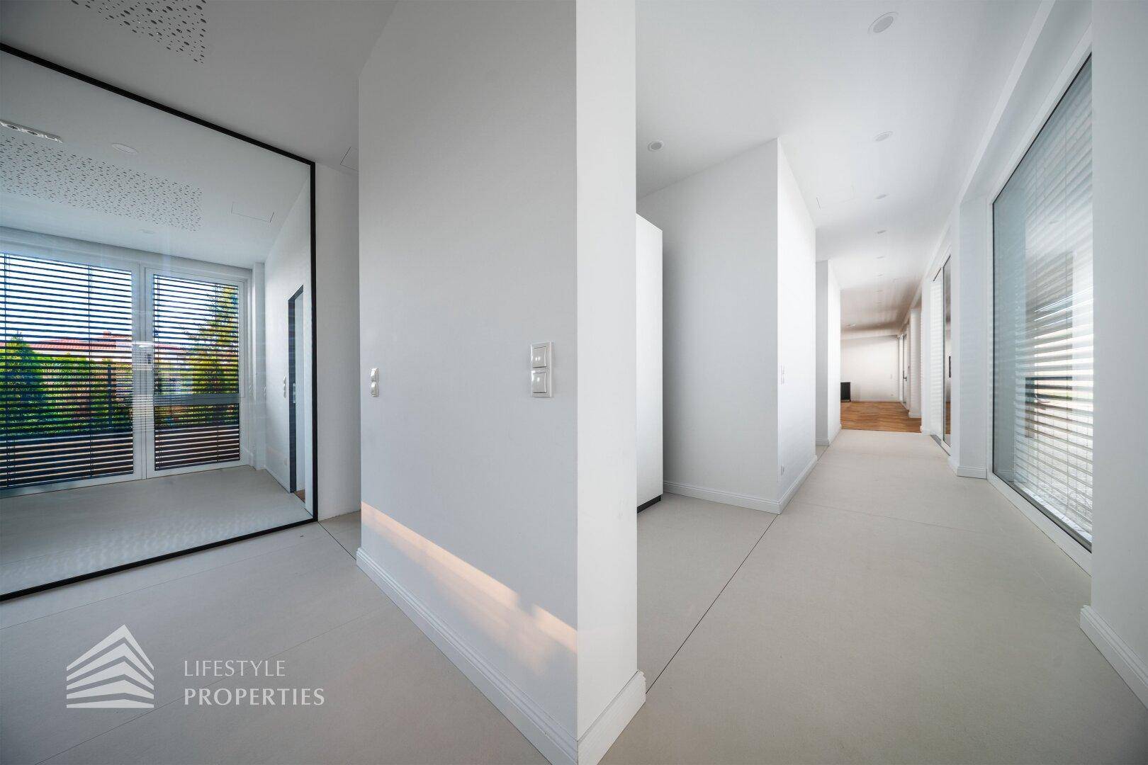 Heller Flur mit großem Spiegel, der ein Fenster und die moderne Architektur widerspiegelt.