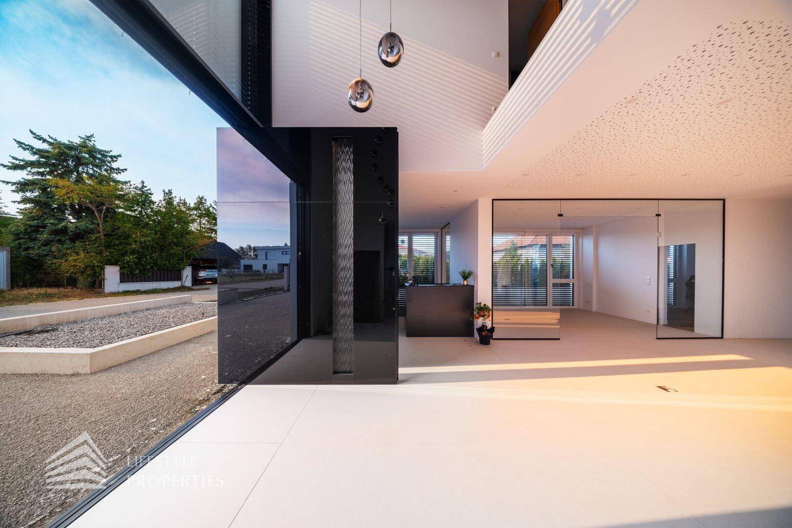 Heller Eingangsbereich mit hohen Decken, großen Glasflächen und modernem Design.