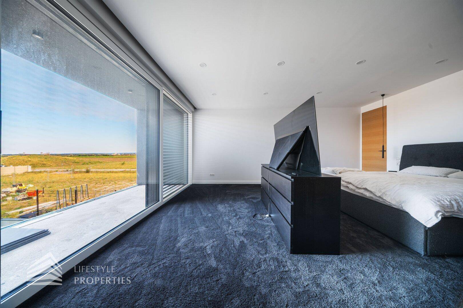 Geräumiges Schlafzimmer mit Teppichboden, großen Fenstern und weitem Blick.