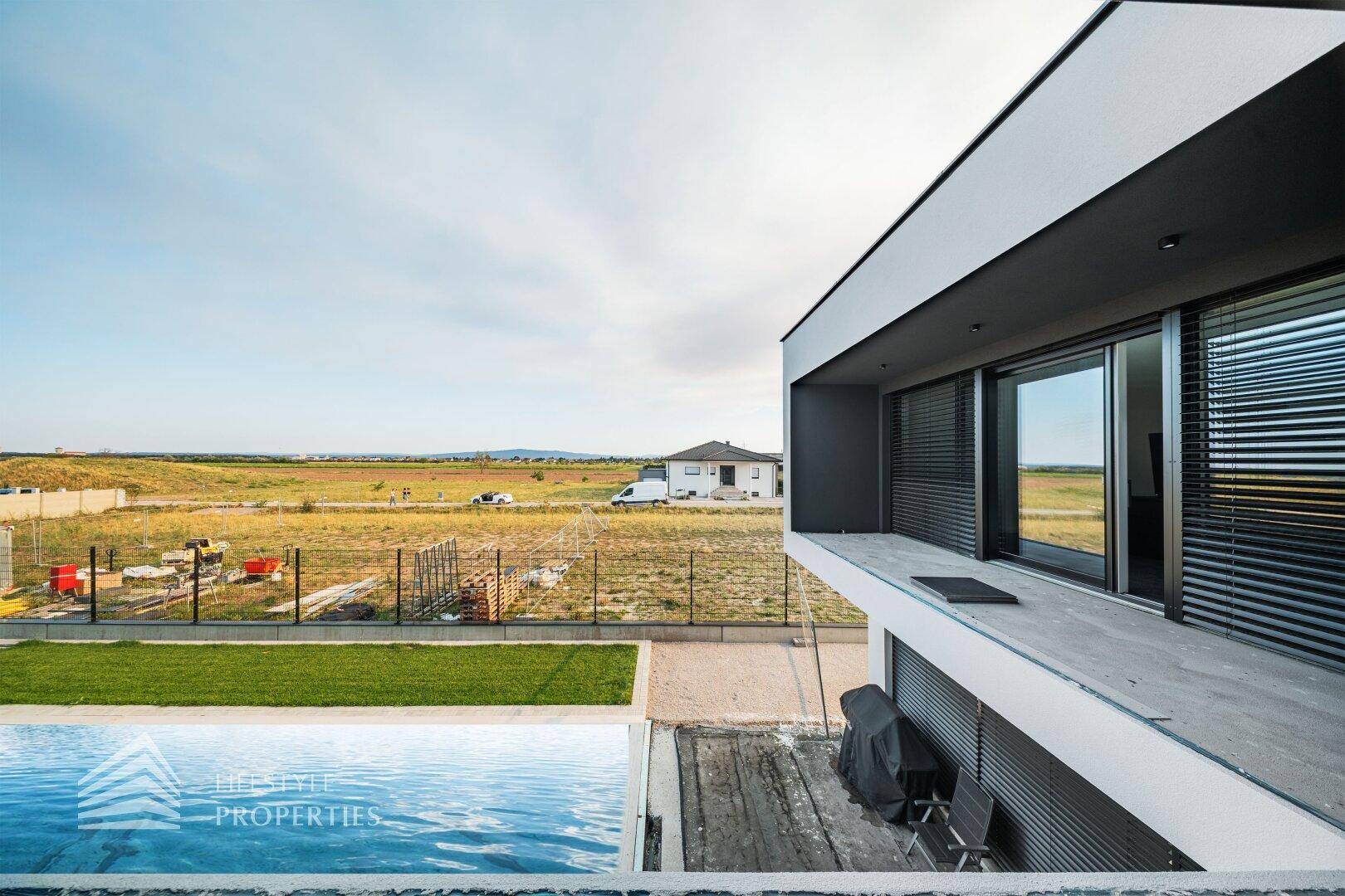 Außenansicht des modernen Hauses mit Pool und weitem Blick auf die offene Landschaft.