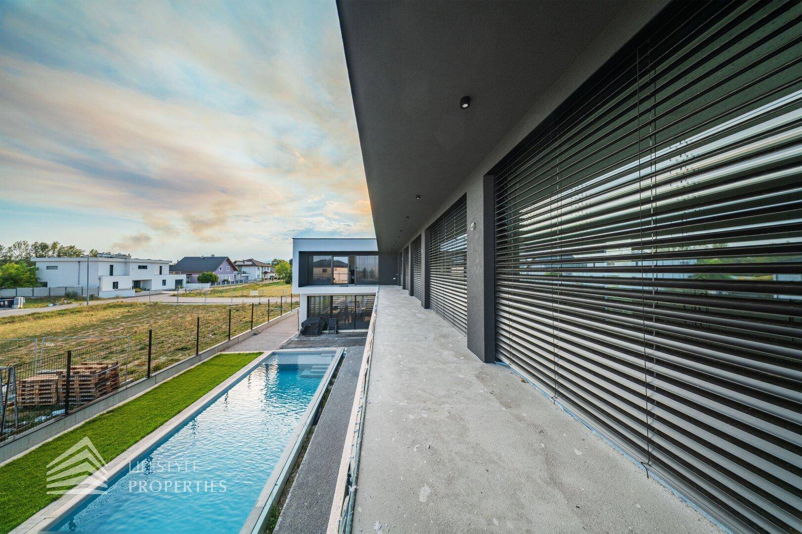 Seitenansicht des modernen Hauses mit Pool und Blick auf die Nachbarschaft und Landschaft.