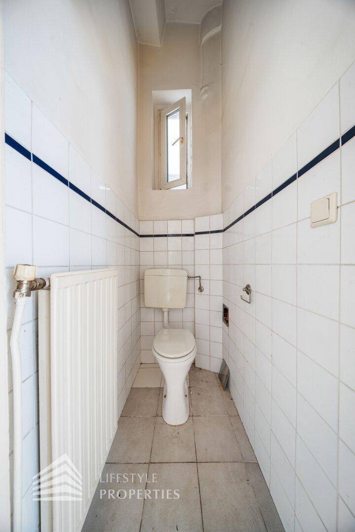Kleines WC mit Fenster, Toilette und Heizkörper, einfach gefliest und funktional.