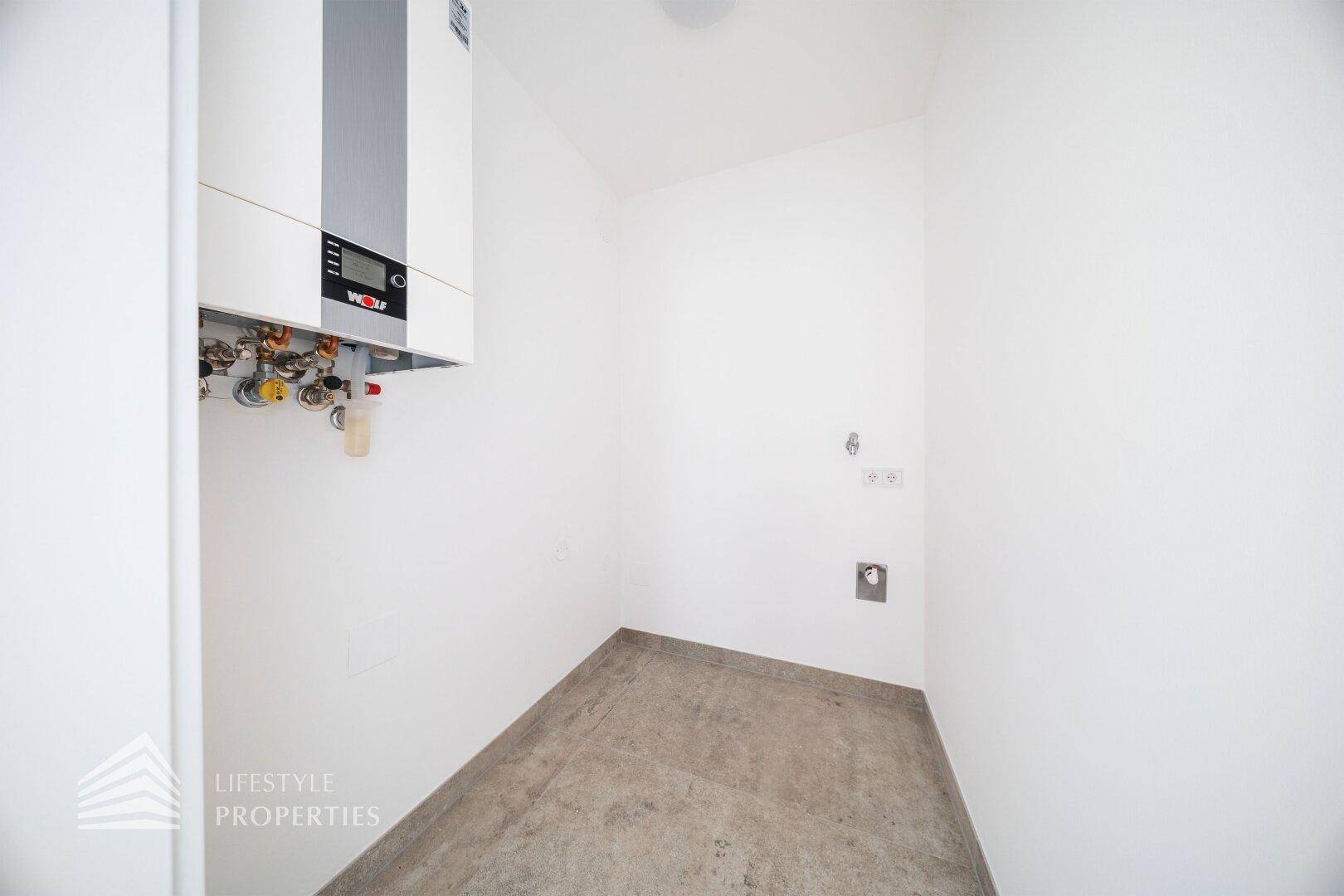 Praktischer Hauswirtschaftsraum mit Heizungsanlage und Anschlüssen für Waschmaschine.