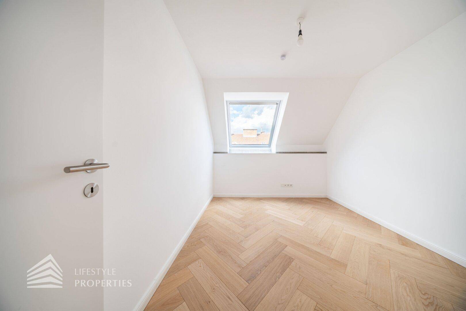 Gemütliches Schlafzimmer im Dachgeschoss mit Fischgrätparkett und einem Dachfenster.