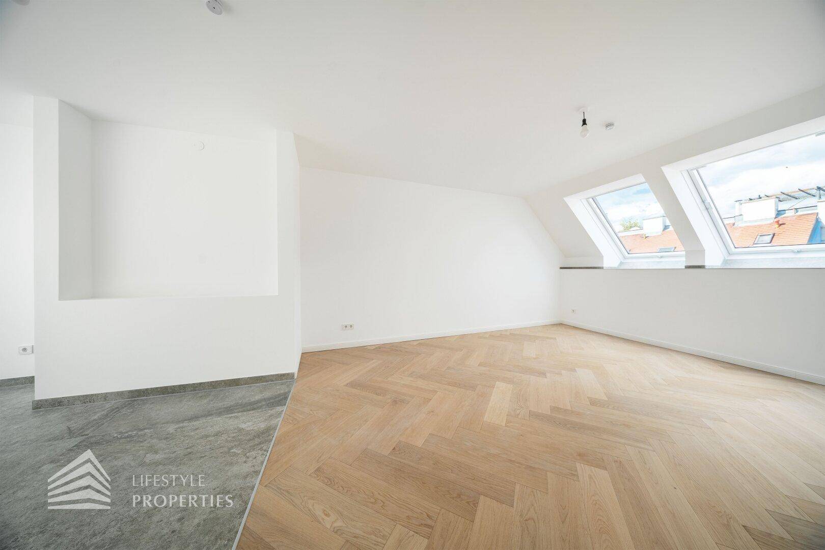 Heller Wohnbereich im Dachgeschoss mit gemischtem Bodenbelag und zwei Dachfenstern.