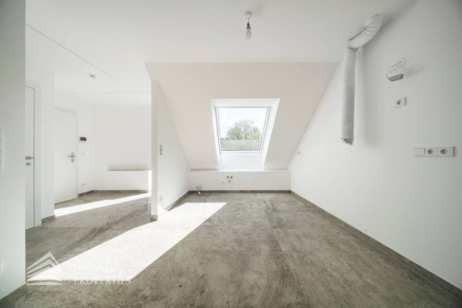 Heller Raum im Dachgeschoss mit grauen Fliesen, Dachfenster und sichtbarer Lüftung.