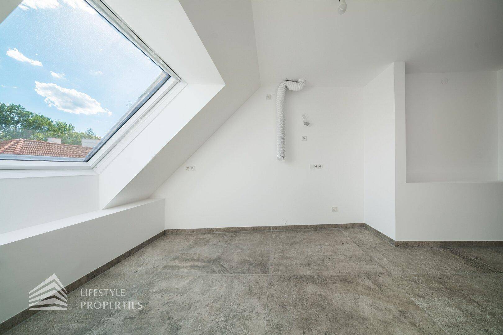 Dachgeschossraum mit grauen Fliesen, Dachfenster und sichtbarer Lüftungsinstallation.