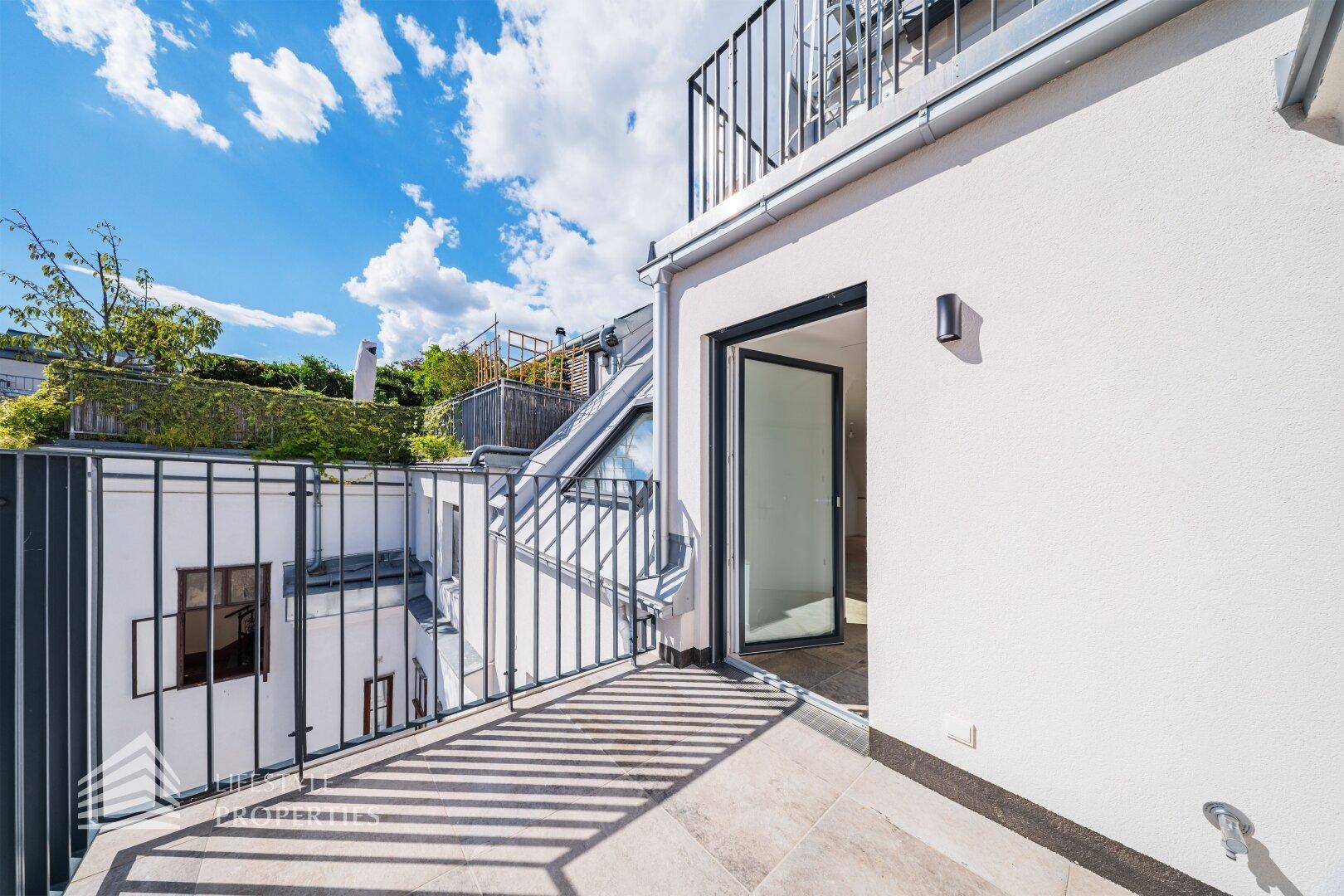 Geräumiger Balkon mit Fliesenboden und Zugang zum Innenbereich des Gebäudes.