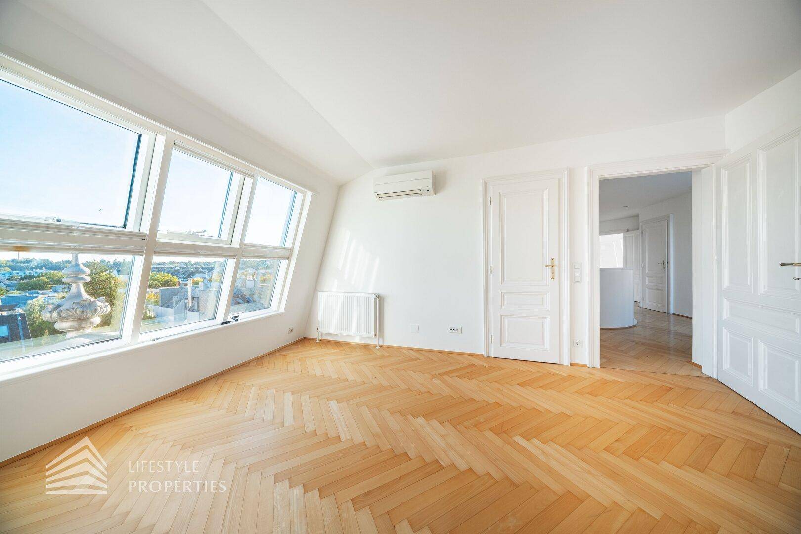 Geräumiges Dachgeschosszimmer mit Fischgrätparkett, Klimaanlage und weitem Ausblick.