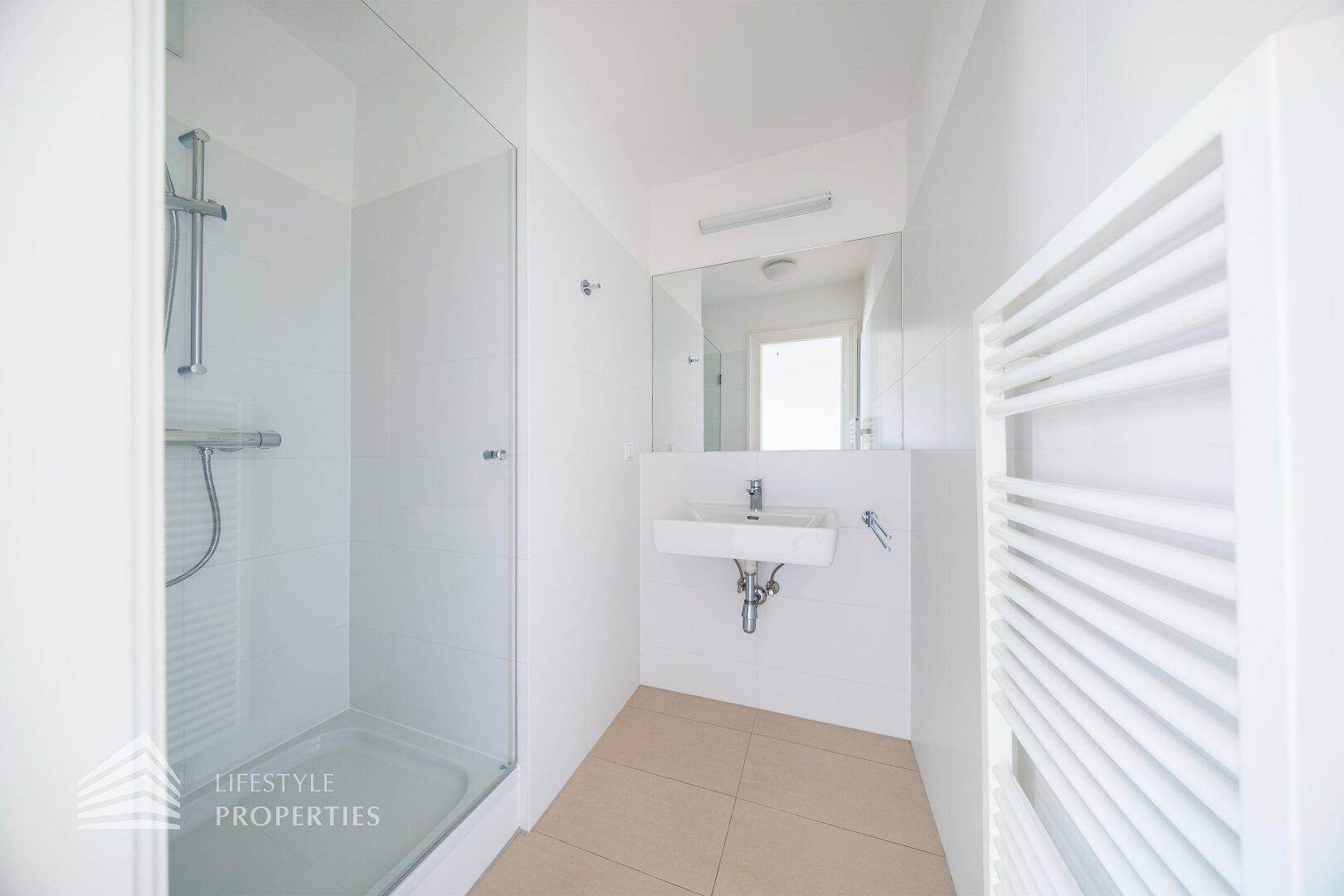 Modernes Badezimmer mit Dusche, Waschbecken und beheiztem Handtuchhalter.