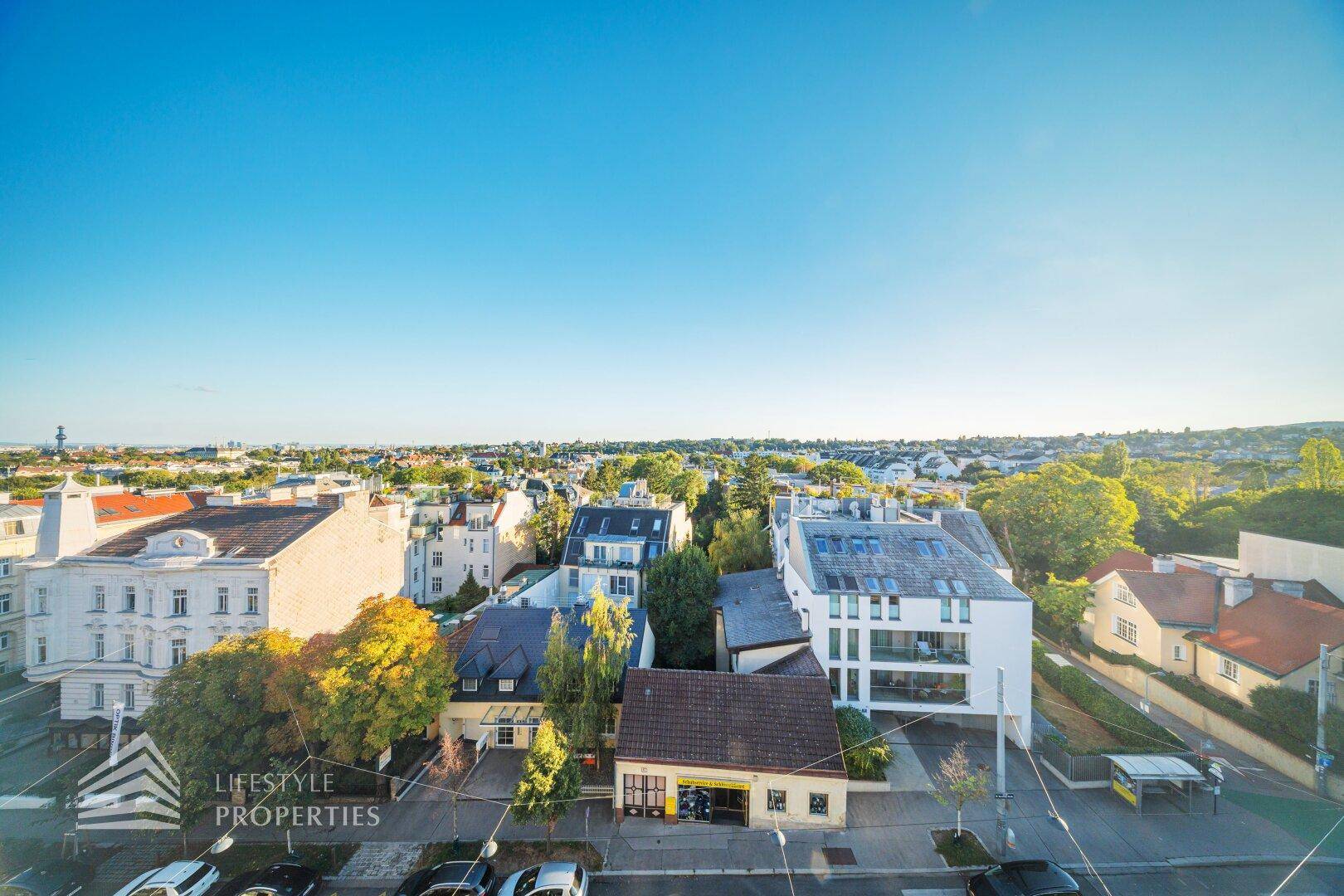 Weitläufiger Blick vom Balkon über die Stadt und die grünen Hügel am Horizont.