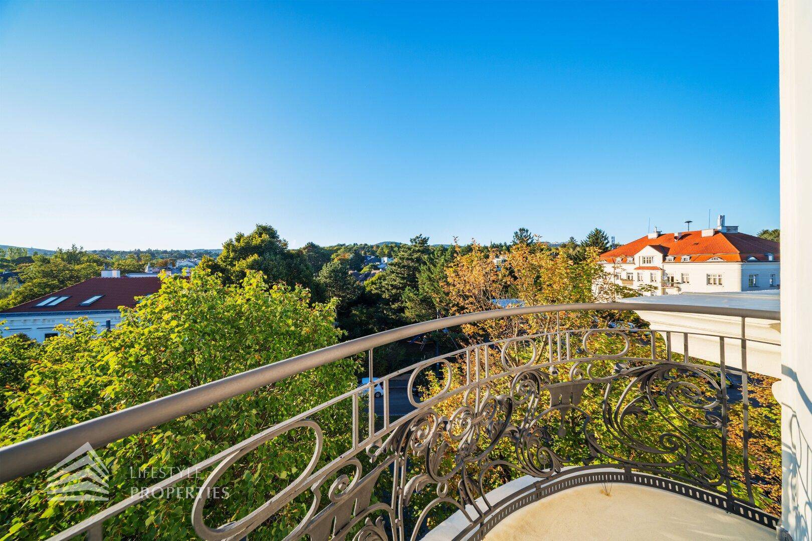Geschwungener Balkon mit schmiedeeisernem Geländer und weitem Blick ins Grüne und auf die Umgebung.