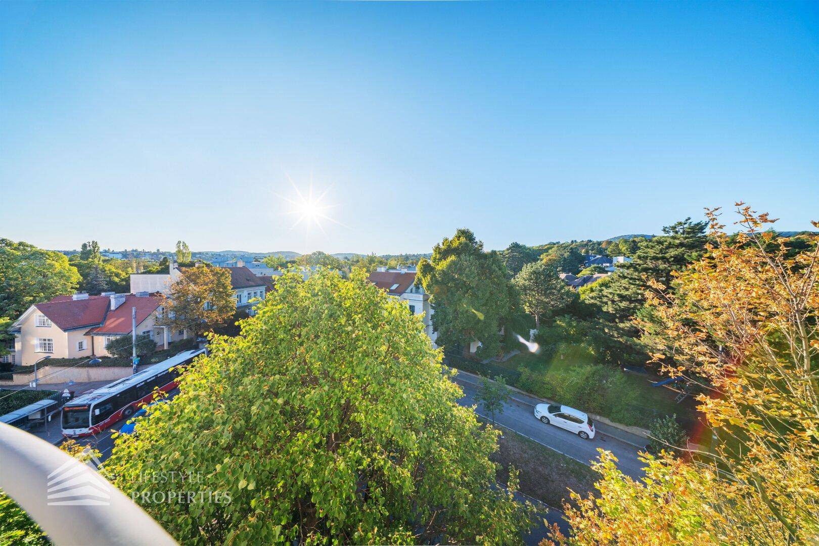 Sonniger Balkon mit weitem Blick über die Stadt und grüne Baumwipfel, ideal zum Entspannen.