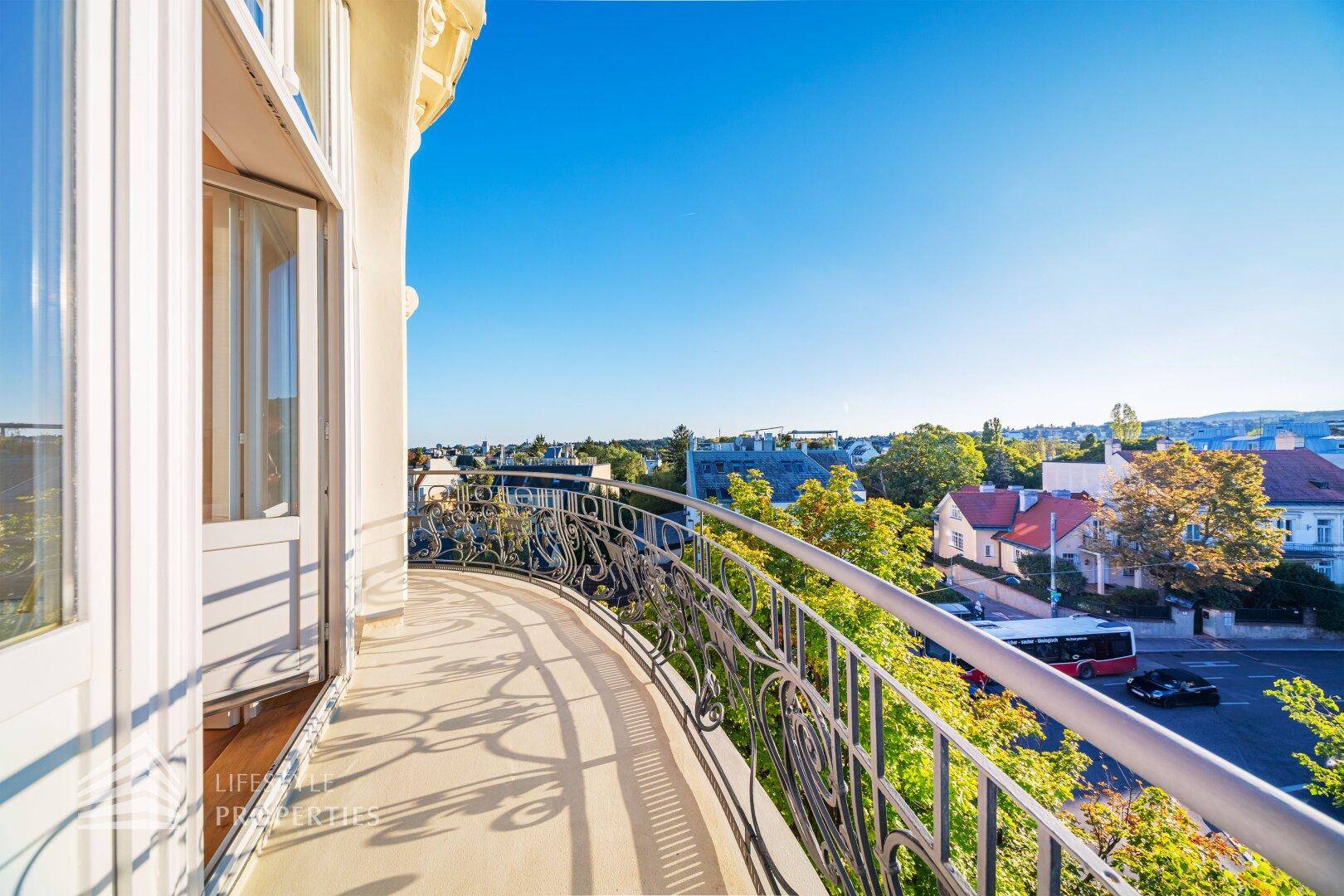 Langer, geschwungener Balkon mit kunstvollem Geländer und Zugang zum Innenbereich, mit Stadtblick.