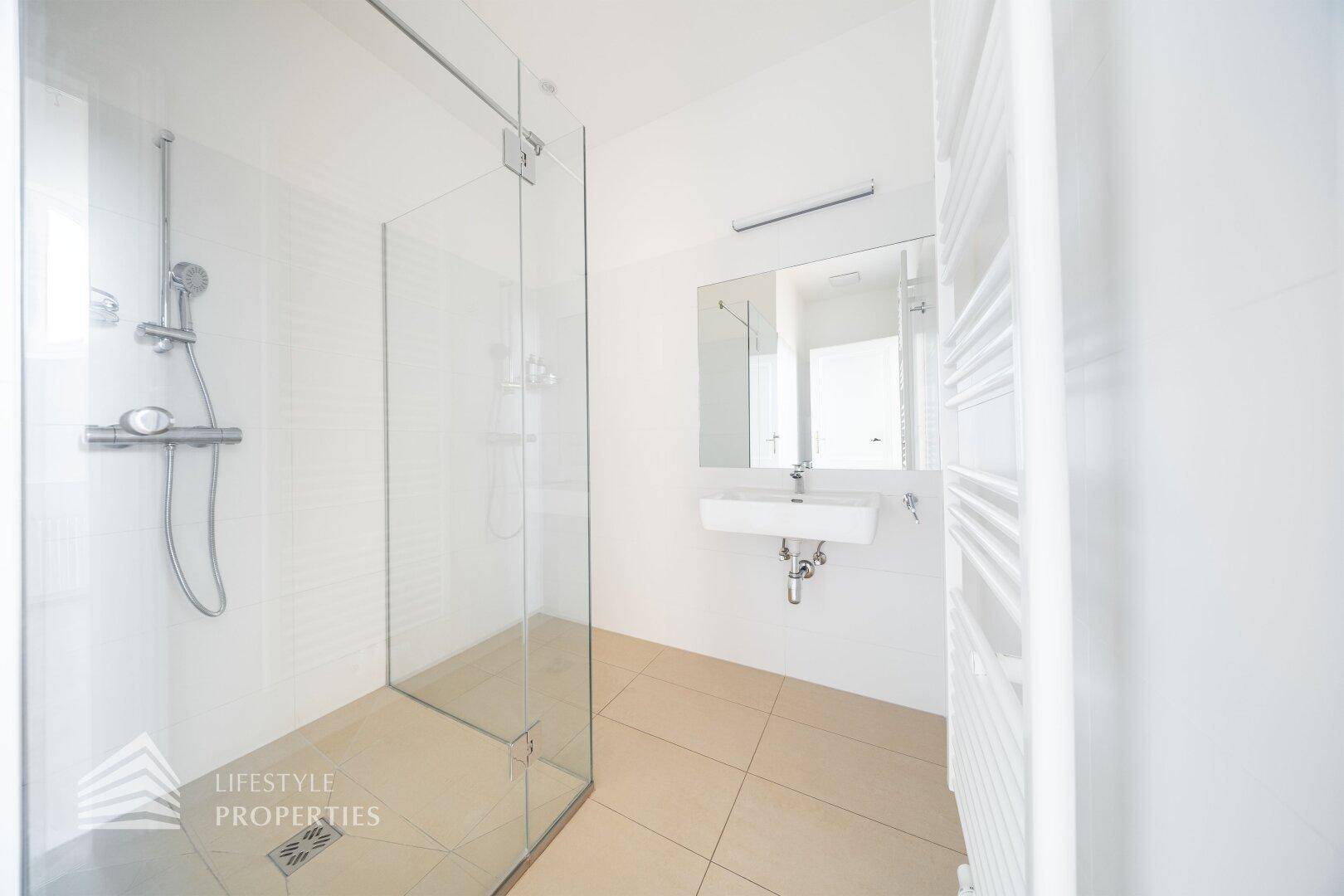Modernes Badezimmer mit großer begehbarer Dusche, Einzelwaschbecken und beheiztem Handtuchhalter.