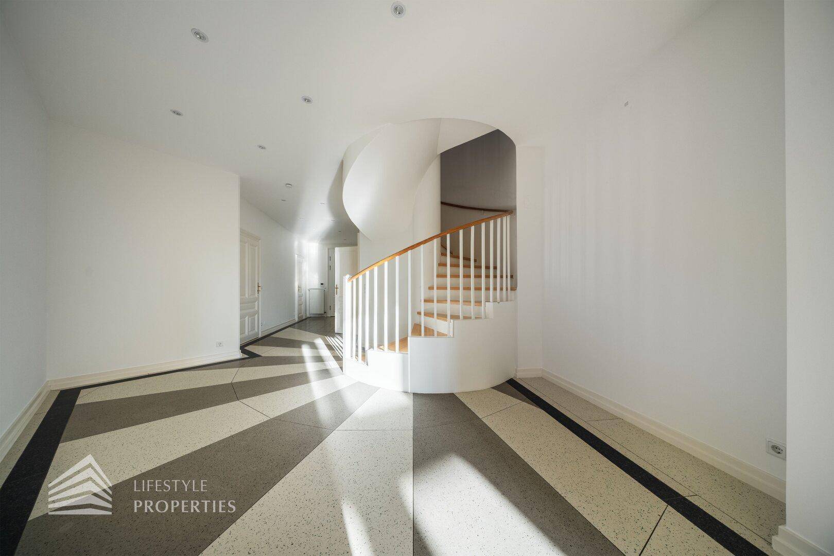 Geräumiger Eingangsbereich mit Wendeltreppe und dekorativem Fliesenboden, sehr hell.