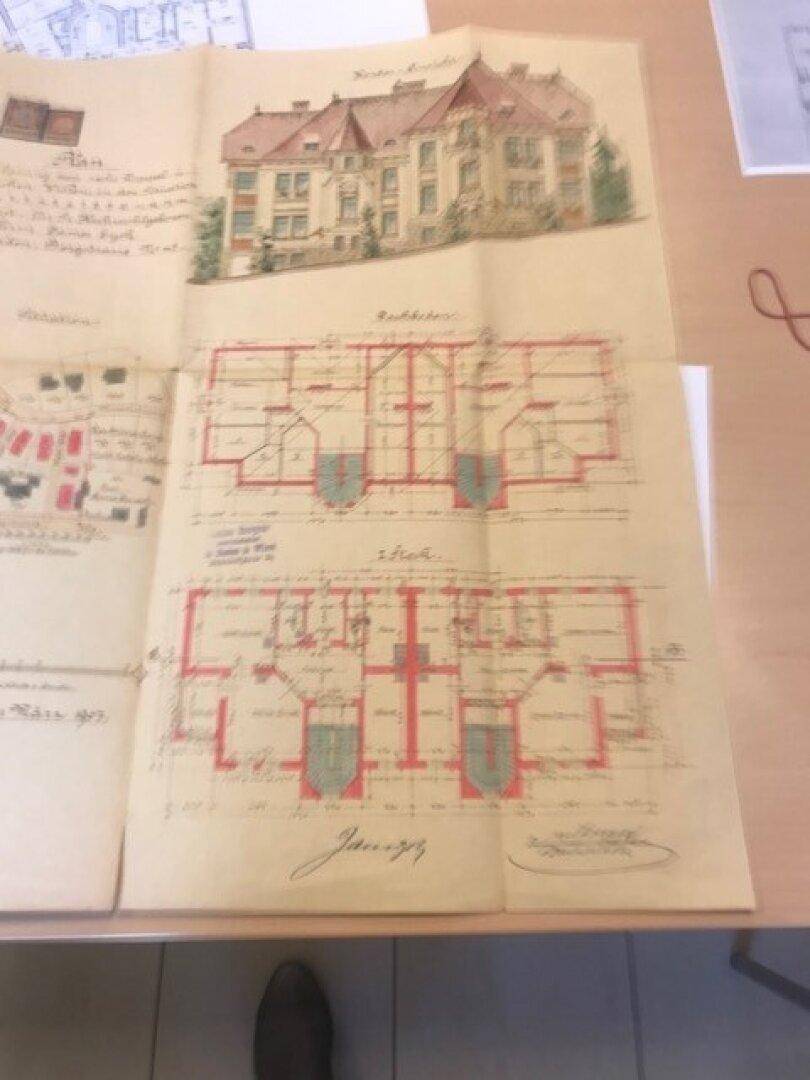 Historischer Grundriss mit Gebäudeansicht und detaillierten Raumaufteilungen.