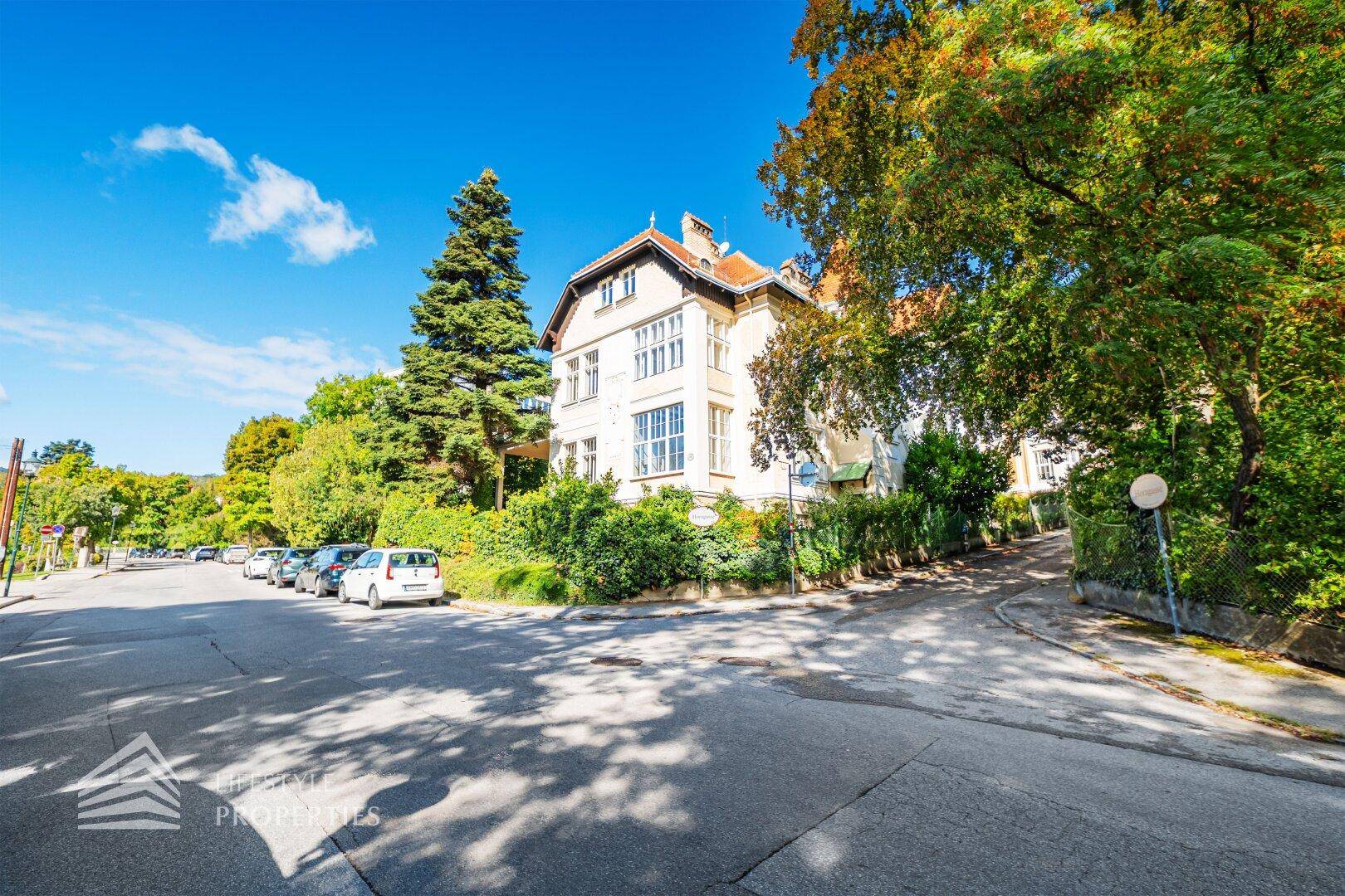 Elegante Villa in einer ruhigen Wohngegend mit altem Baumbestand und sonnigem Wetter.