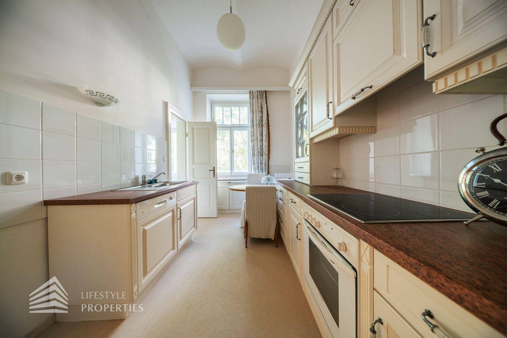 Traditionelle Küche mit hellen Schränken, Holz-Arbeitsplatten und Fenster mit Essbereich.