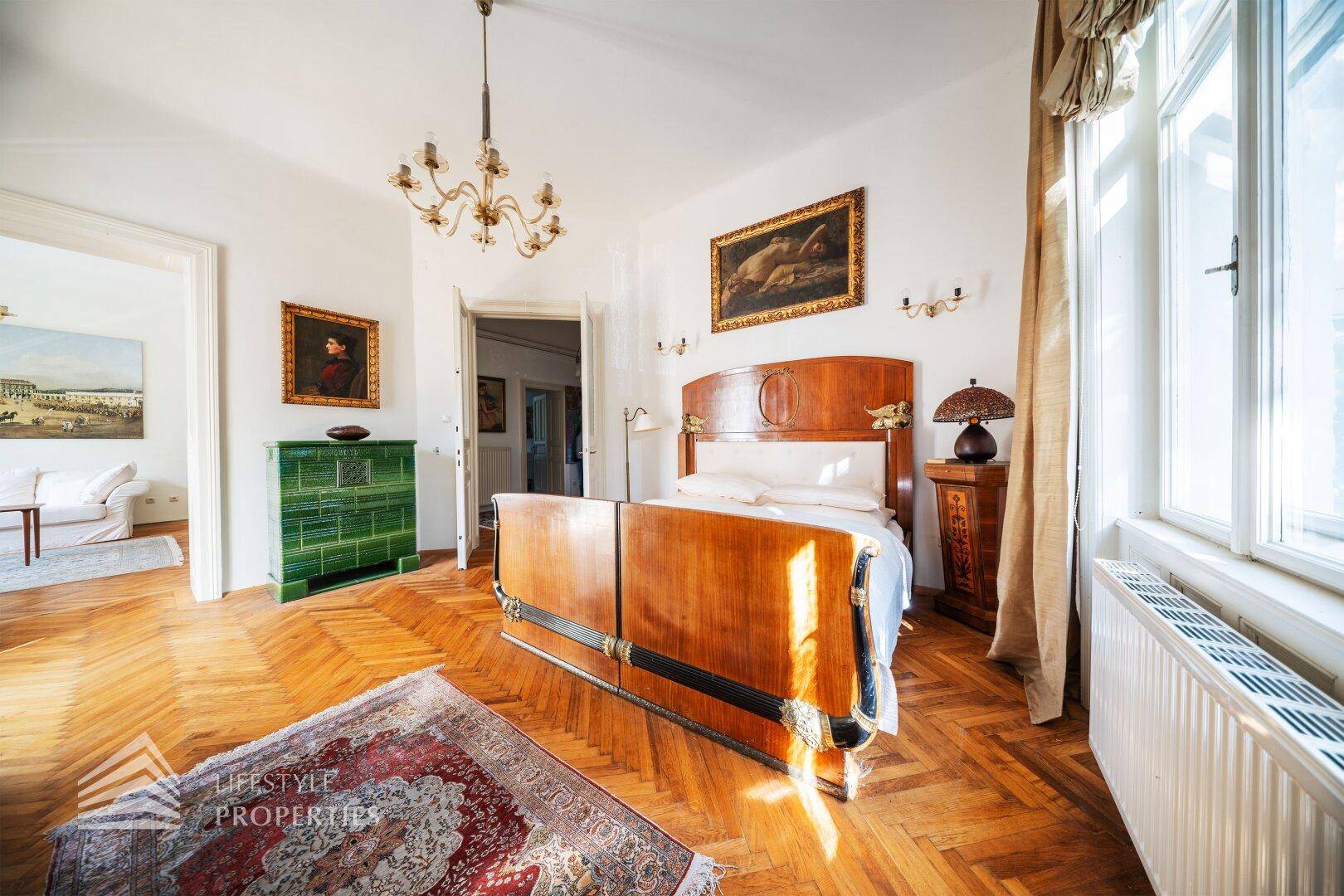 Geräumiges Schlafzimmer mit klassischem Mobiliar, Parkettboden und großen Fenstern.