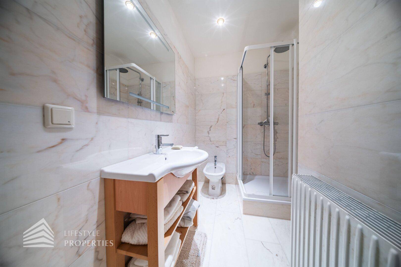 Modernes Badezimmer mit Dusche, Bidet und Marmorfliesen.