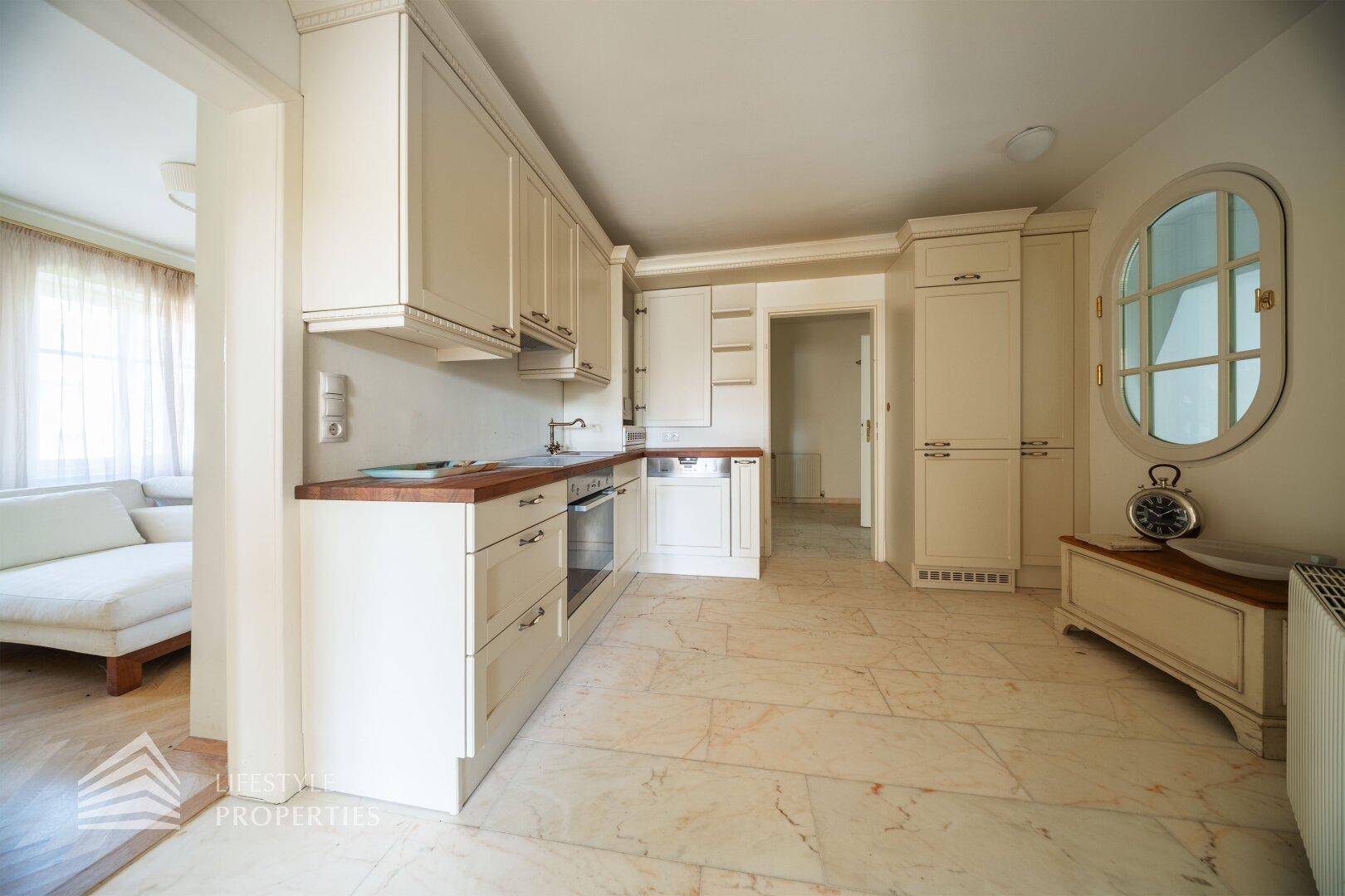 Moderne helle Küche mit Holztheke, Einbaugeräten und Fliesenboden.