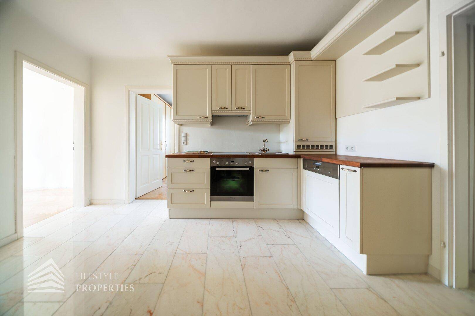 Helle Einbauküche mit modernen Geräten, Holztheke und Marmorfliesen.