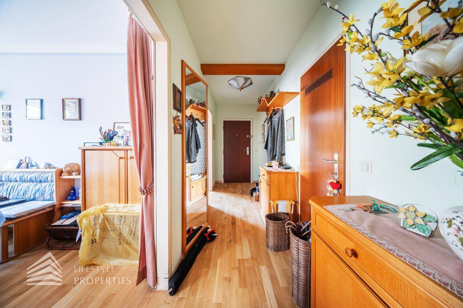 Heller Flur mit Holzboden, Garderobe und Blick auf die Eingangstür.