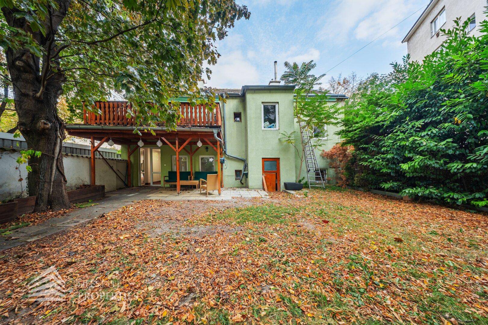 Großer Garten mit Rasenfläche, Bäumen und Blick auf die Rückseite des Gebäudes.