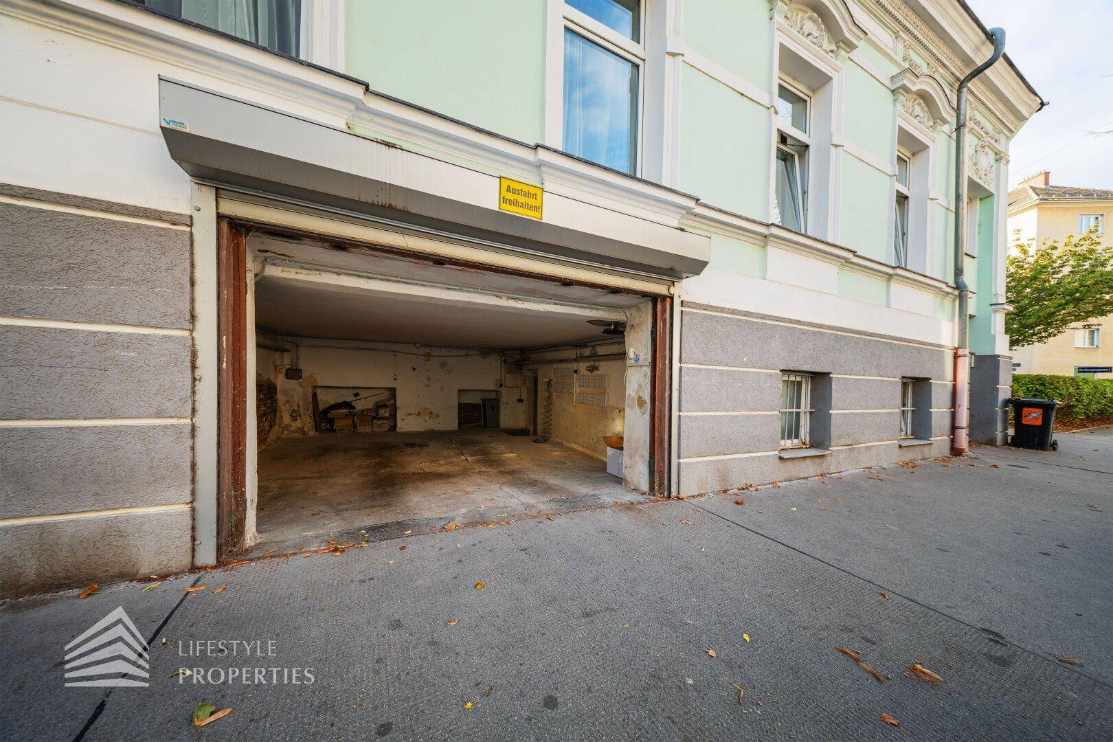 Außenansicht eines Gebäudes mit Garageneinfahrt und Rolltor.