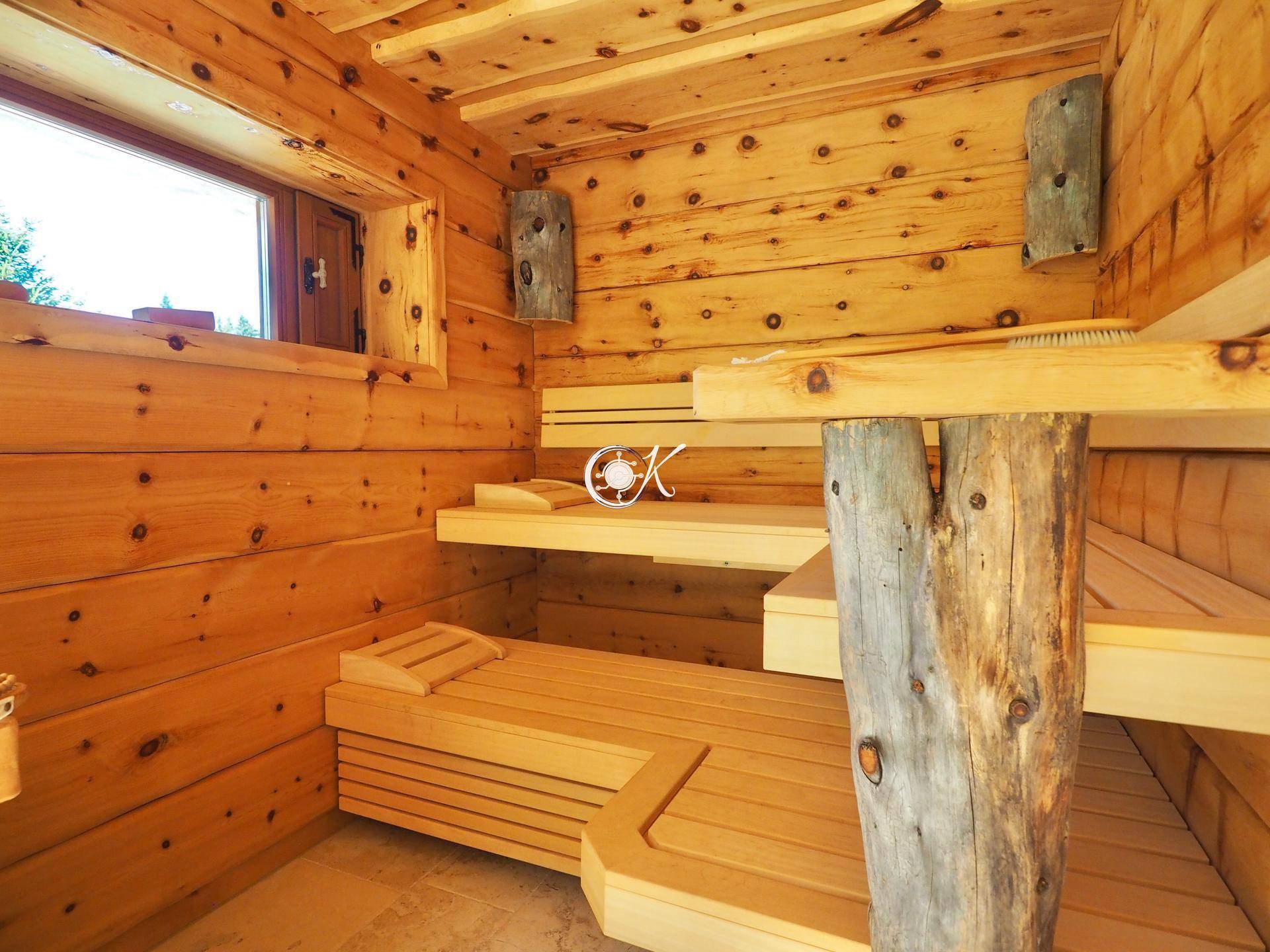 Traditionelle Holzsauna mit mehreren Bänken und einem Fenster für natürliches Licht.