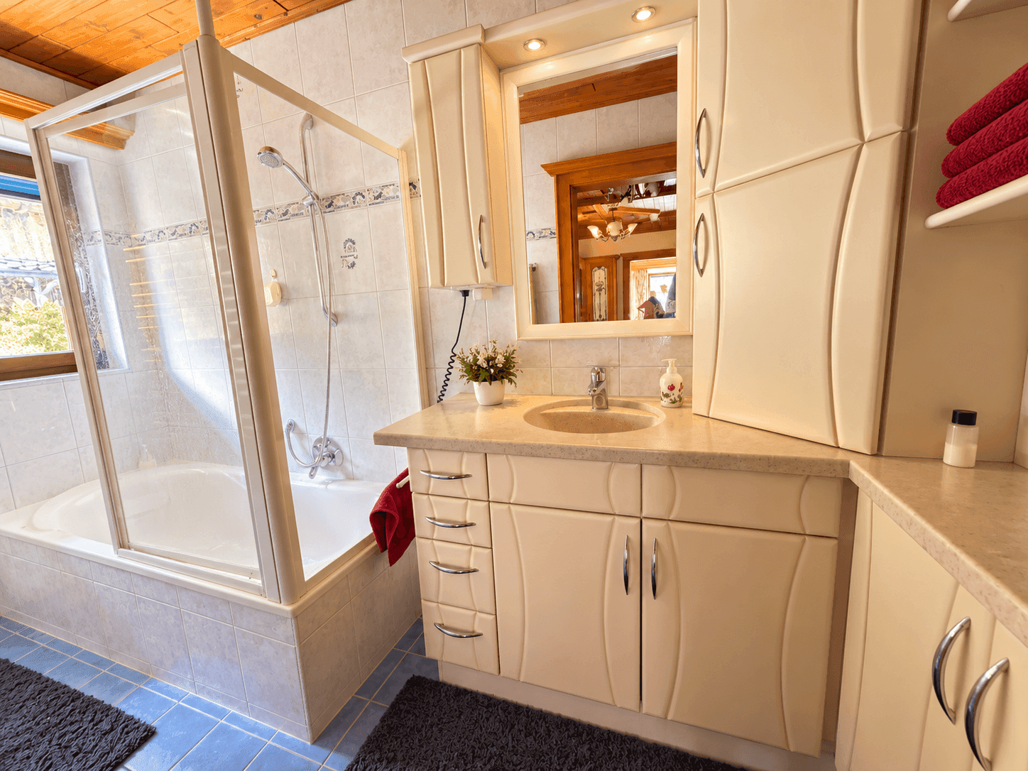 Modernes Badezimmer mit Dusch-Badewannen-Kombination, Waschtisch und Fenster für Tageslicht.