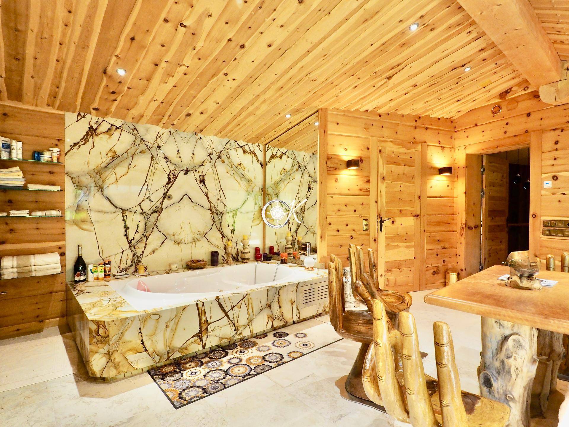 Geräumiges Badezimmer mit Whirlpool-Badewanne, Holzwänden und Steinboden.