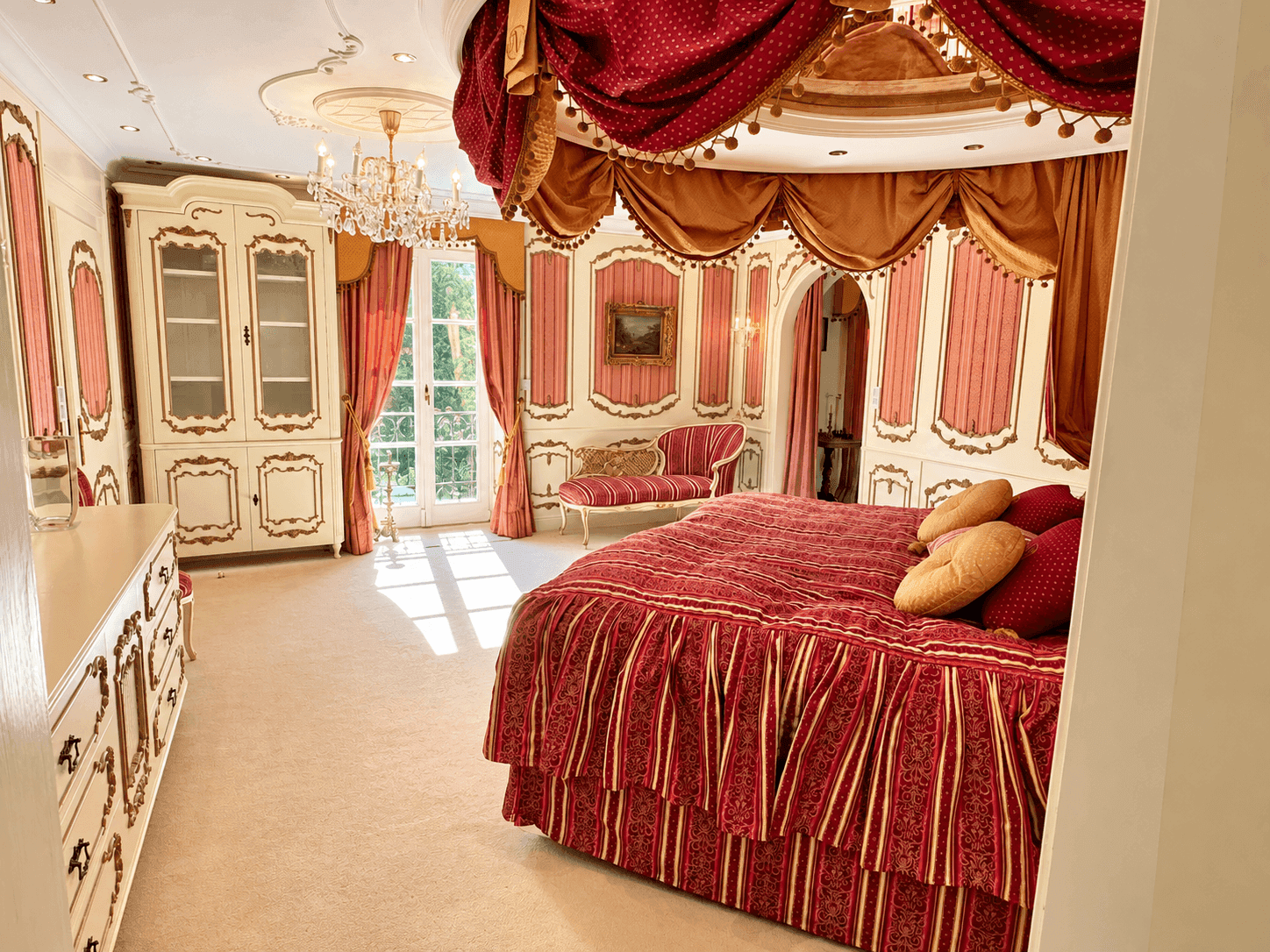 Großzügiges Schlafzimmer mit luxuriösem Himmelbett, Stuckdecke und Zugang zum Außenbereich.