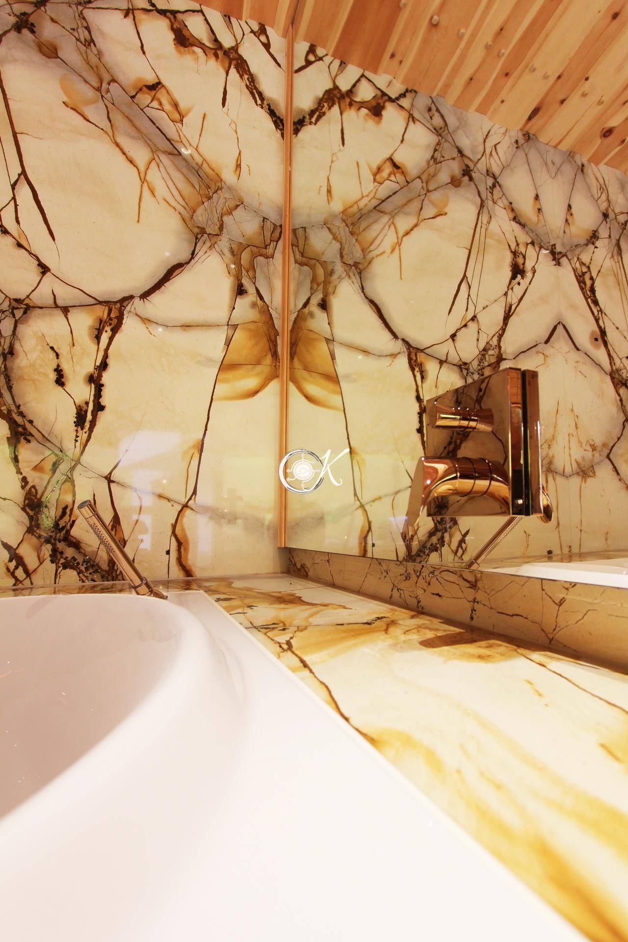 Detailansicht einer Badewanne mit luxuriöser Steinverkleidung und modernen Armaturen.
