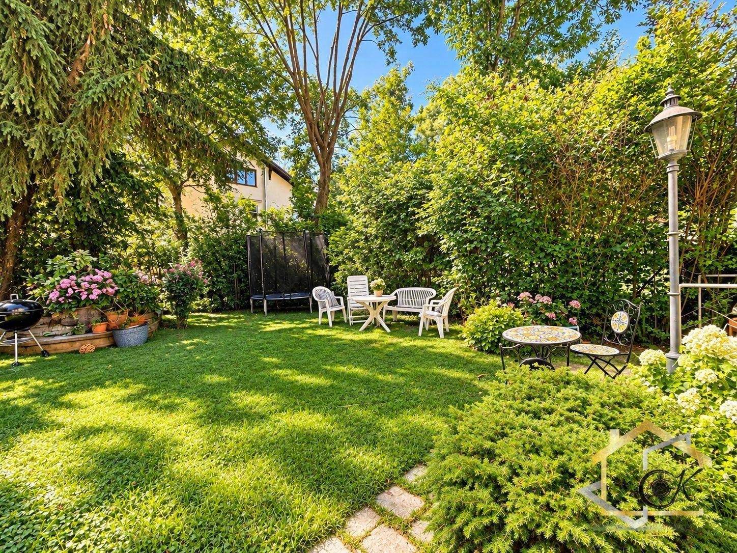 Sonniger, gepflegter Garten mit Rasenfläche, Sitzgruppen, Grill und altem Baumbestand.