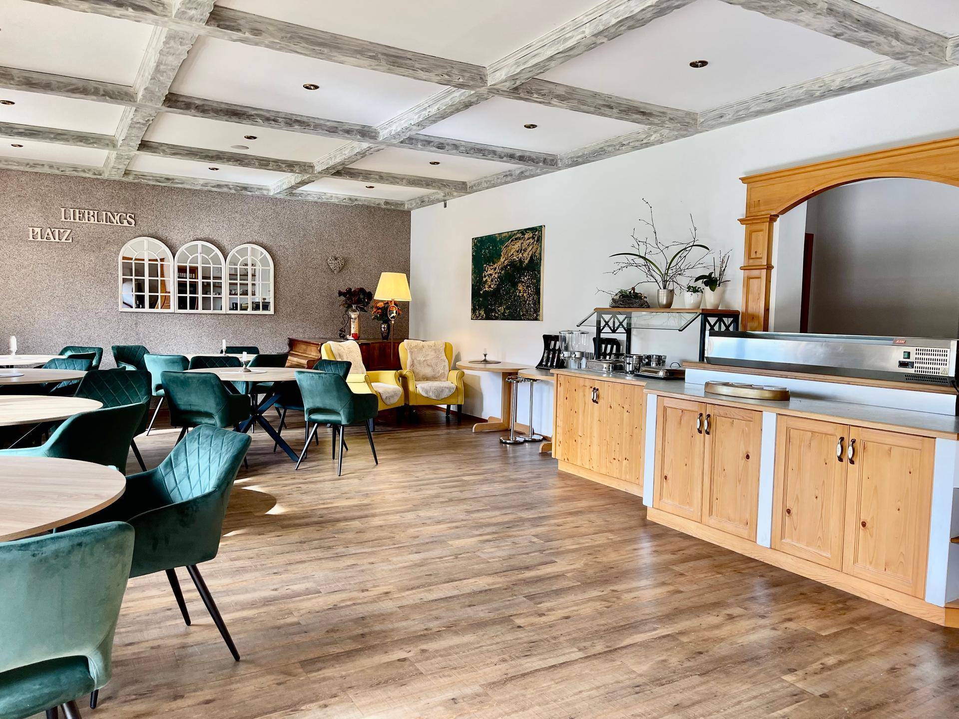 Geräumiger Speisesaal mit Holzboden, Kassettendecke und modernen grünen Stühlen.