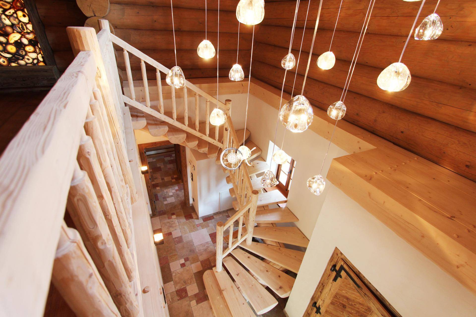 Helle Holztreppe mit Galerie und moderner Hängeleuchte in einem rustikalen Interieur.