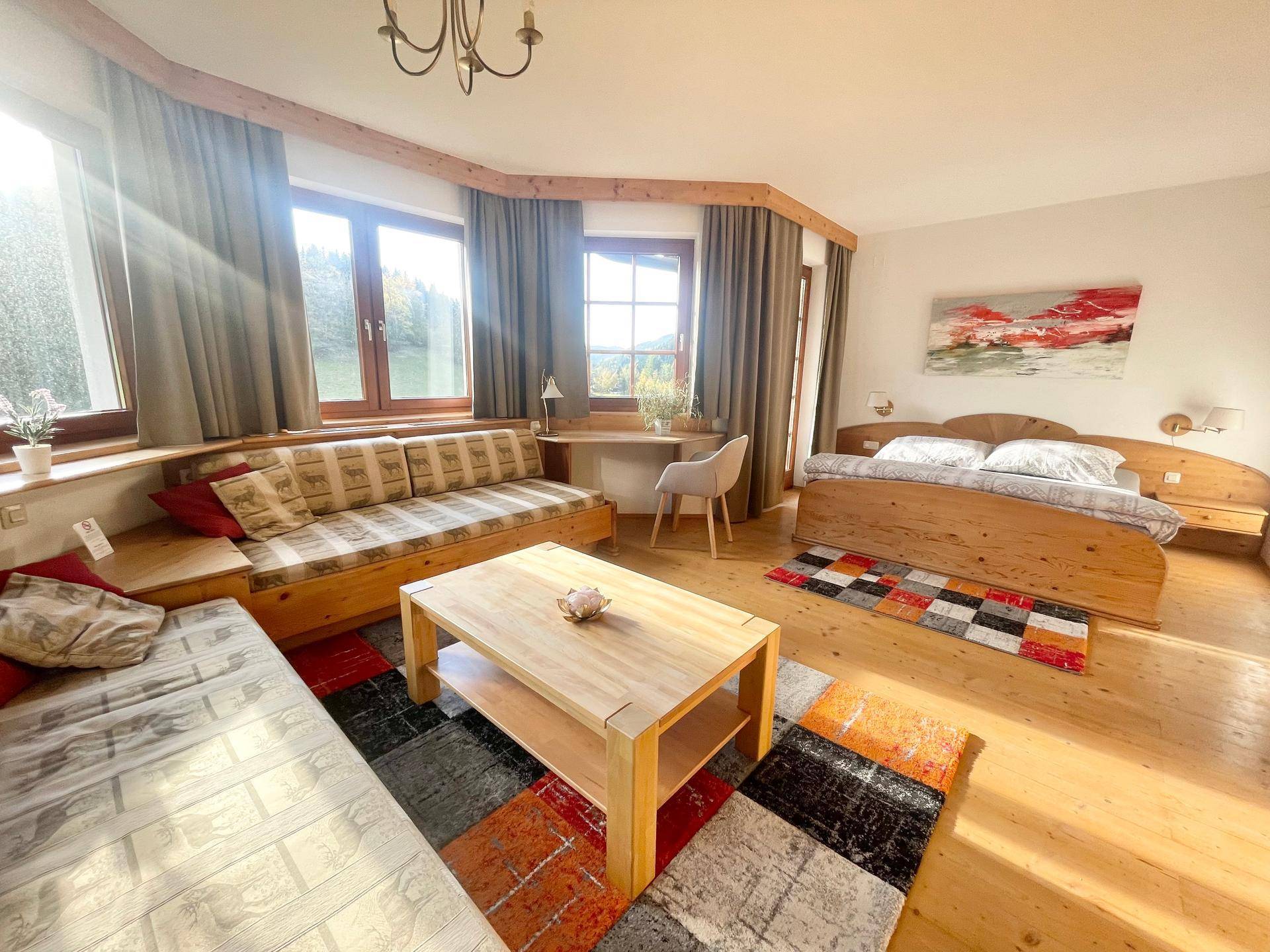 Helles Schlafzimmer mit Holzbett, Tagesbett, Schreibtisch und Holzboden im traditionellen Stil.