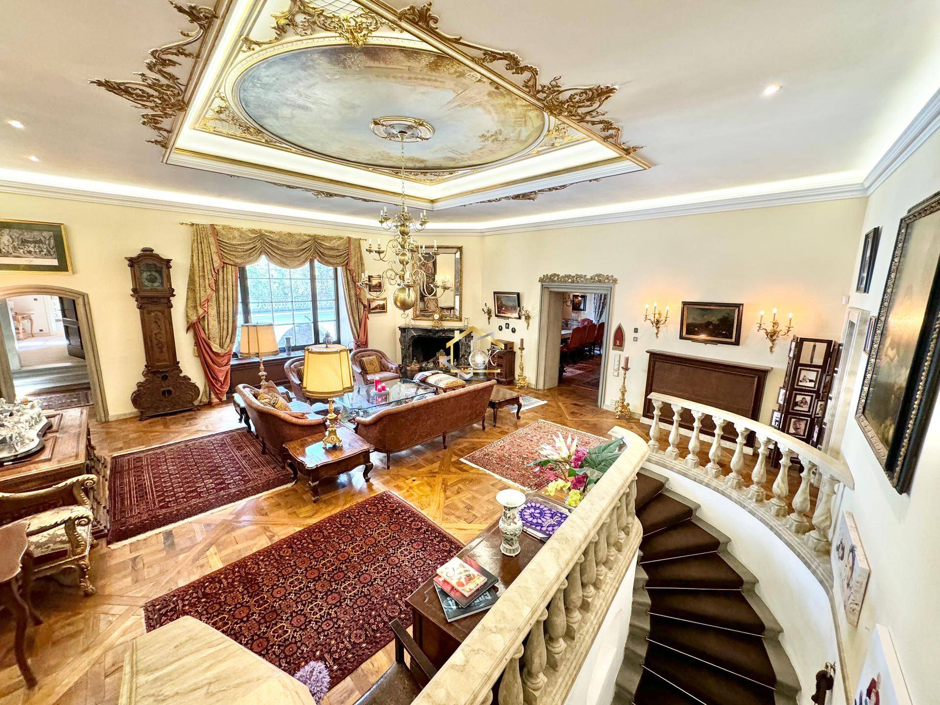 Prunkvolles Wohnzimmer mit kunstvoller Deckenmalerei, Parkettboden und eleganter Treppe.