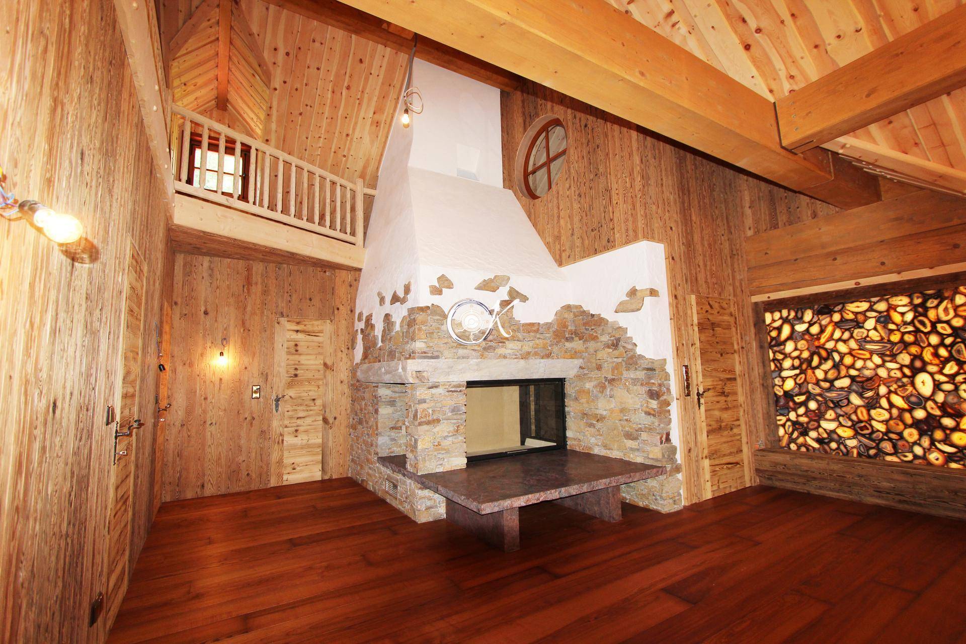 Geräumiger Raum mit Holzwänden, Steinwand und einem großen Kamin.